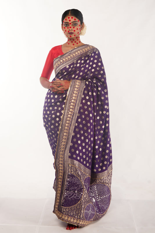 Woman wearing a purple saree with gold patterns on a white background