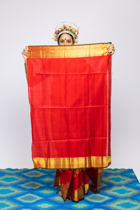 A woman wearing a red kanjiveram silk wedding saree designed by Ayush Kejriwal.