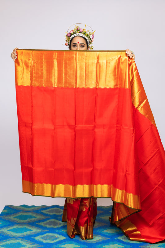 A woman wearing a red and gold kanjiveram silk wedding saree designed by Ayush Kejriwal.