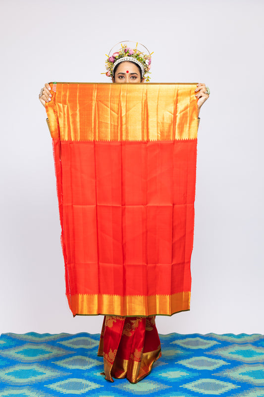 A woman wearing a red and gold kanjiveram silk wedding saree designed by Ayush Kejriwal.