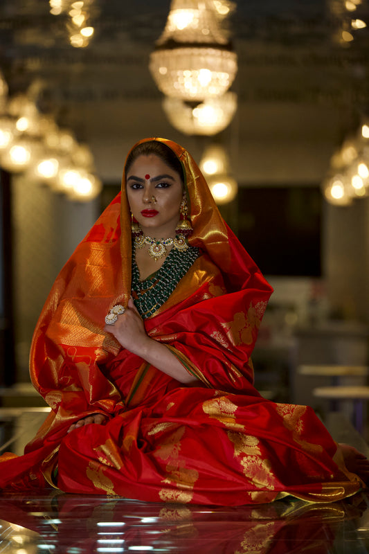 A woman wearing a red kanjiveram silk wedding saree designed by Ayush Kejriwal.