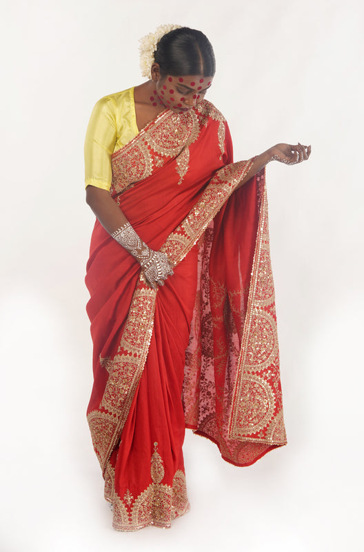 A woman wearing a red embroidered wedding saree designed by Ayush Kejriwal.