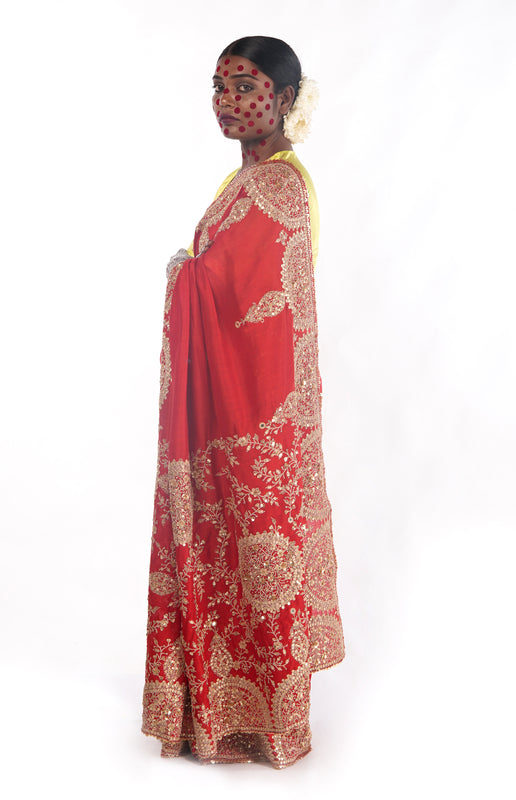 A woman wearing a red embroidered wedding saree designed by Ayush Kejriwal.