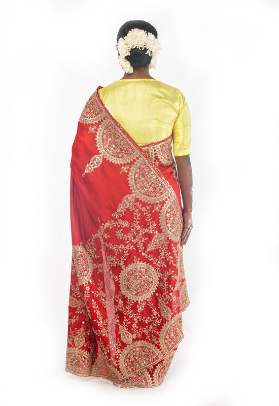 A woman wearing a red embroidered wedding saree designed by Ayush Kejriwal.