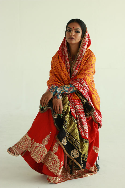 A woman wearing a red embroidered wedding saree designed by Ayush Kejriwal.