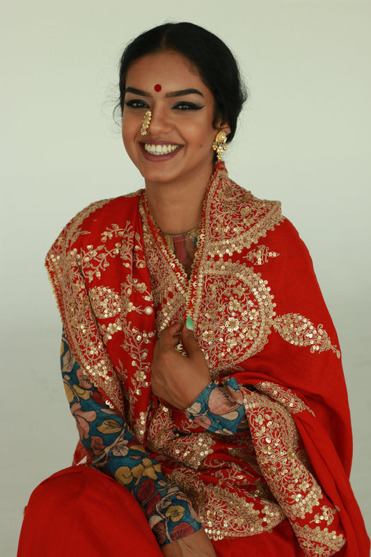 A woman wearing a red embroidered wedding saree designed by Ayush Kejriwal.