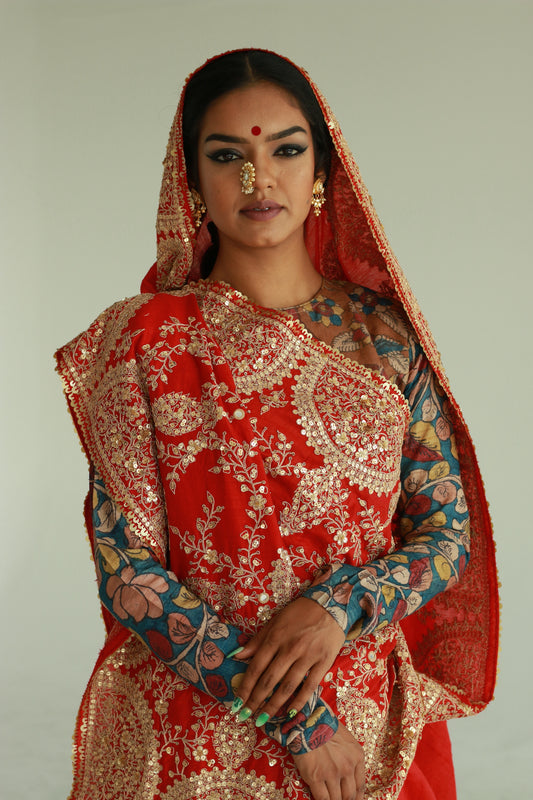 A woman wearing a red embroidered wedding saree designed by Ayush Kejriwal.