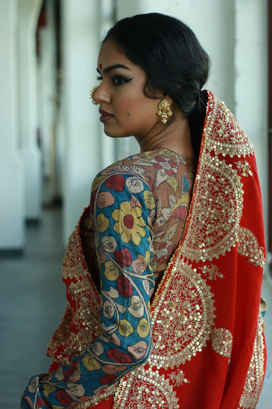 A woman wearing a red embroidered wedding saree designed by Ayush Kejriwal.