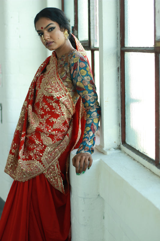A woman wearing a red embroidered wedding saree designed by Ayush Kejriwal.