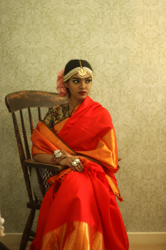 A woman wearing a red and gold kanjiveram silk wedding saree designed by Ayush Kejriwal.