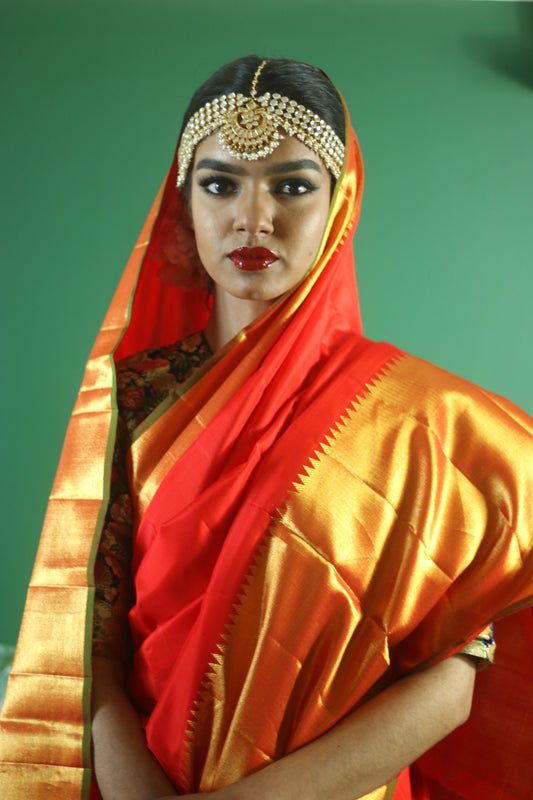 A woman wearing a red and gold kanjiveram silk wedding saree designed by Ayush Kejriwal.