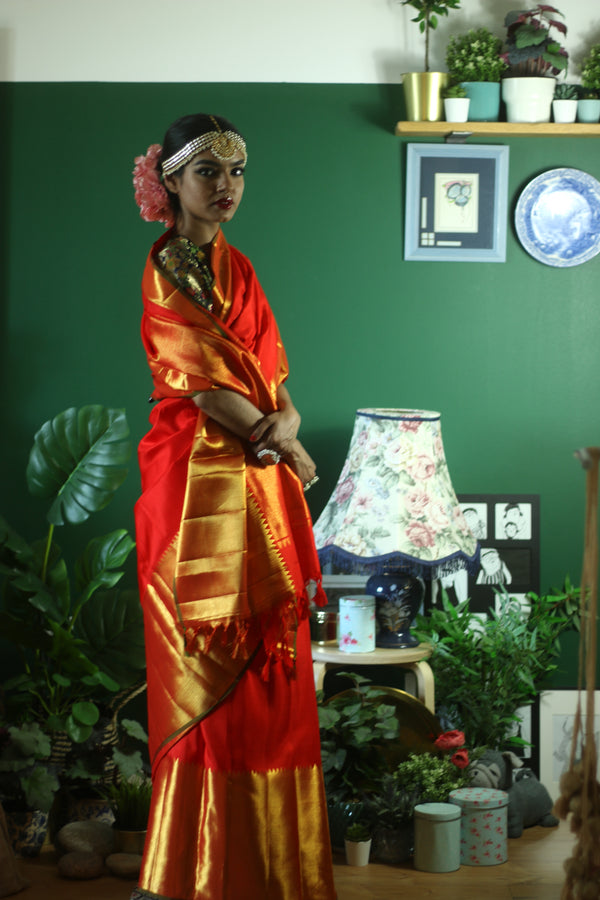 A woman wearing a red and gold kanjiveram silk wedding saree designed by Ayush Kejriwal.