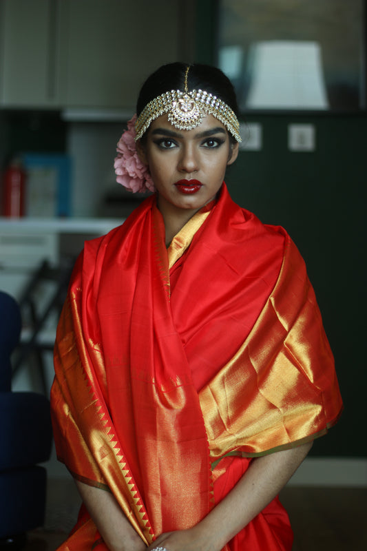 A woman wearing a red and gold kanjiveram silk wedding saree designed by Ayush Kejriwal.