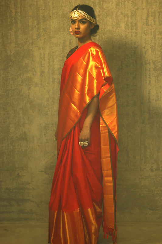 A woman wearing a red and gold kanjiveram silk wedding saree designed by Ayush Kejriwal.