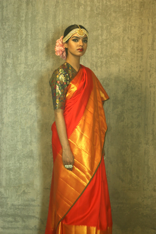 A woman wearing a red and gold kanjiveram silk wedding saree designed by Ayush Kejriwal.