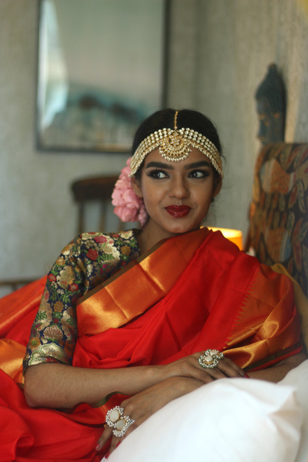 A woman wearing a red and gold kanjiveram silk wedding saree designed by Ayush Kejriwal.