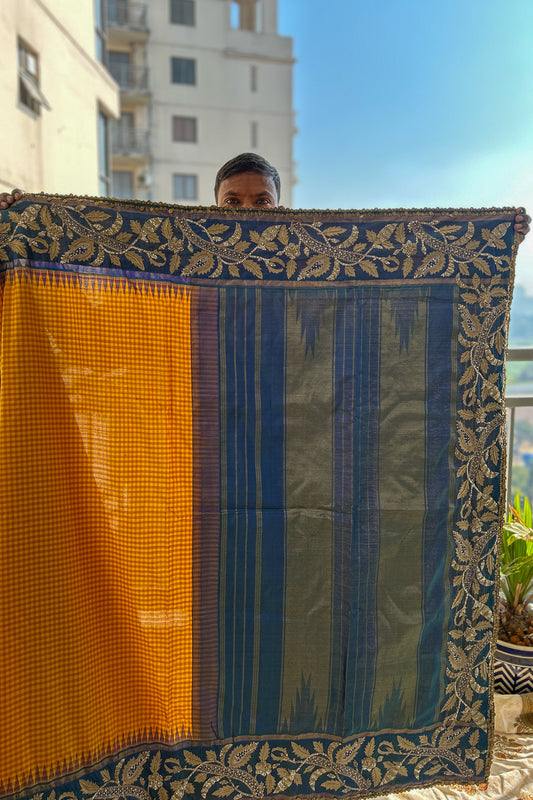 Person holding a kanjiveeram silk saree with intricate patterns against a cityscape background