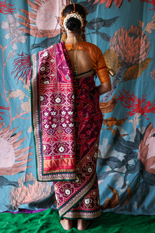 Person wearing a traditional handcrafted authentic hand embroidered patola silk saree with a colorful background