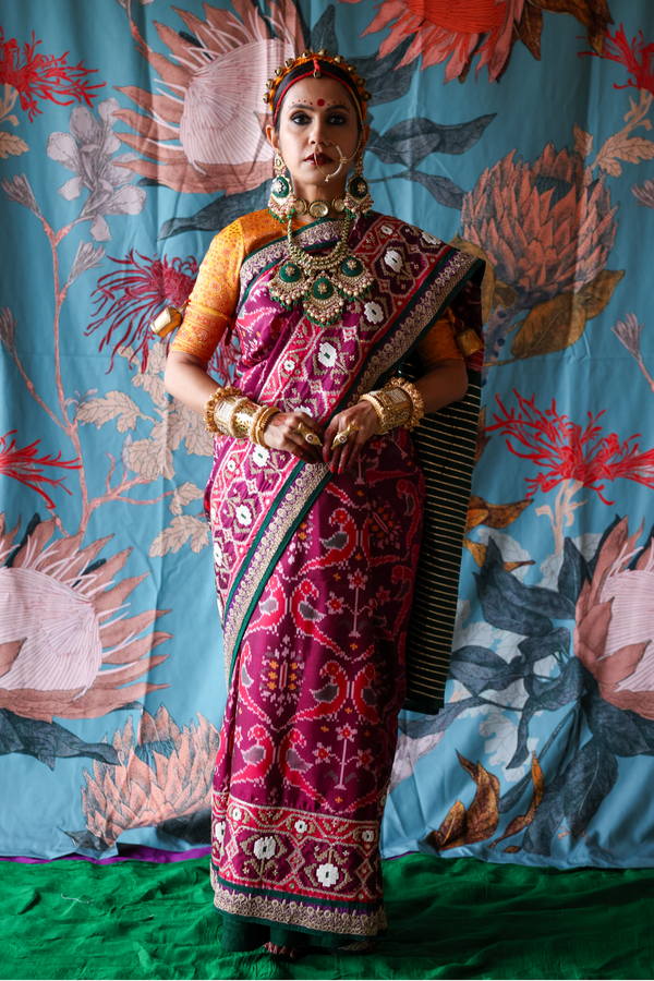 Person wearing a traditional handcrafted authentic hand embroidered patola silk saree with a colorful background