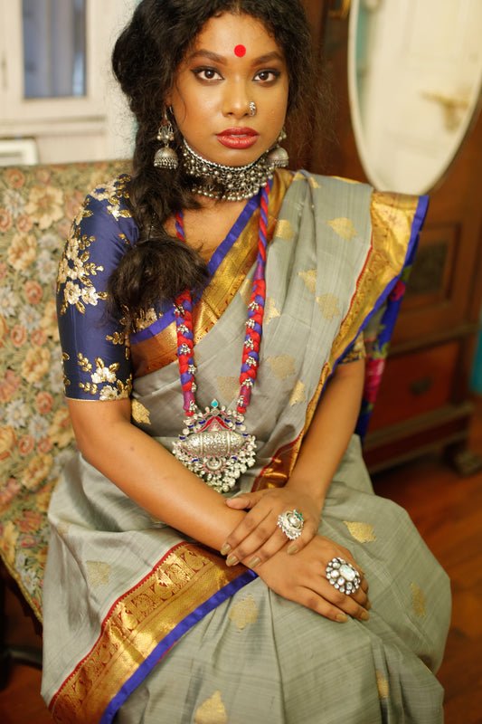 Woman in traditional beautiful handwoven English grey and antique gold Kanjiveeram silk saree with jewelry indoors