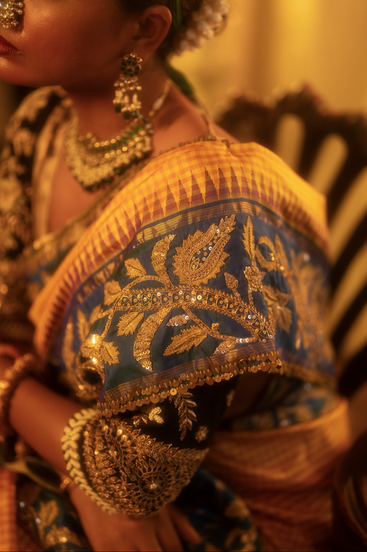 Close-up of a person wearing traditional jewelry and a kanjiveeram silk saree with intricate patterns.