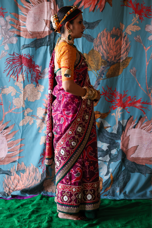Person wearing a traditional handcrafted authentic hand embroidered patola silk saree with a colorful background