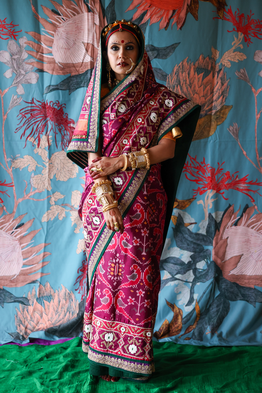 Person wearing a traditional handcrafted authentic hand embroidered patola silk saree with a colorful background