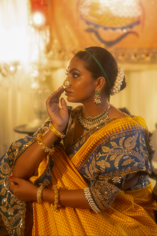 Woman in traditional yellow and blue kanjiveeram silk saree with jewelry indoors