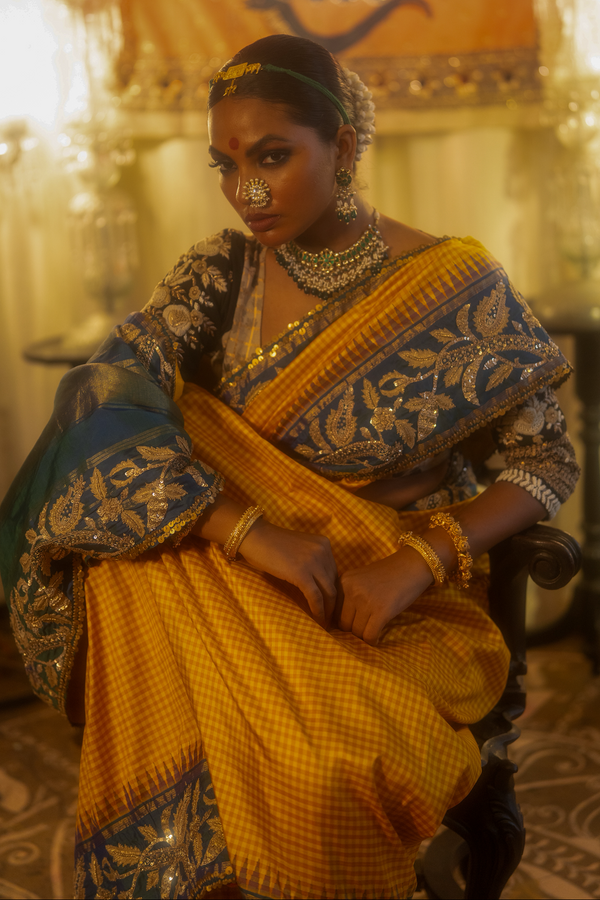 Woman in a yellow kanjiveeram silk saree in an indoor setting