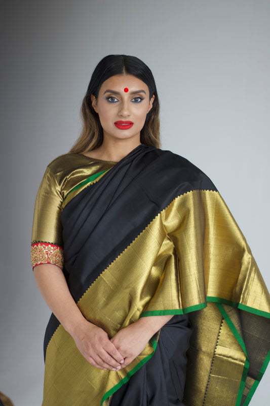 A woman wearing a handwoven black and gold kanjiveram silk saree designed by Ayush Kejriwal.