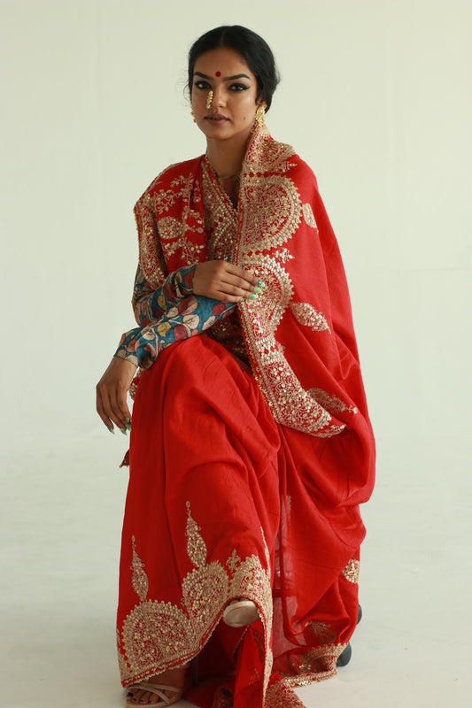 A woman wearing a red embroidered wedding saree designed by Ayush Kejriwal.